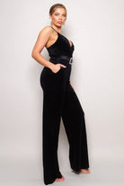Chic black velvet holiday party jumpsuit outfit with a stylish belt and pockets for a fashionable look