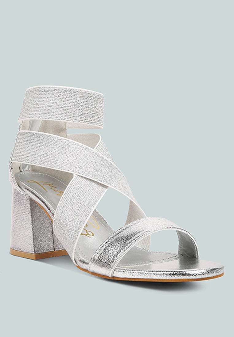 Silver glittery sandal with a block heel on a light gray background