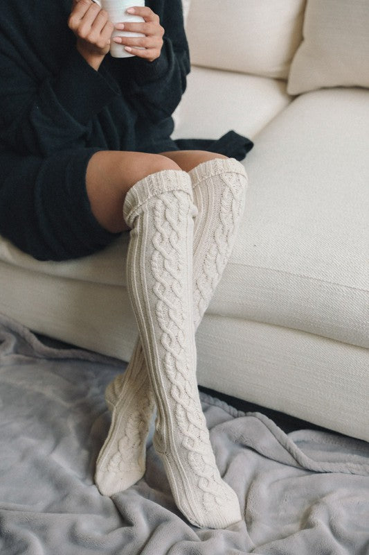 Cozy women's knee high cable knit socks in cream, perfect for lounging at home