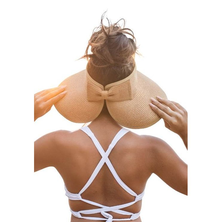 Woman wearing a large brim bow beach hat with a stylish design, perfect for sunny days at the beach.