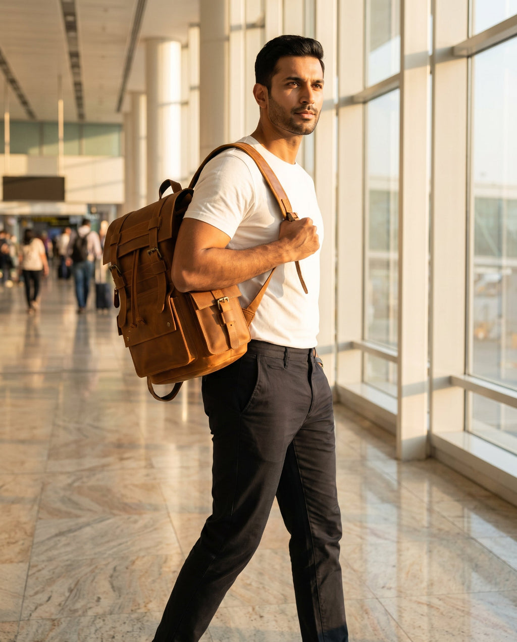 Man with leather backpack walking through airport departure hall, golden morning light