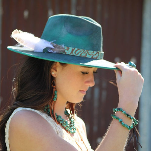 Woman wearing leather fringe turquoise earrings with a stylish hat and matching jewelry
