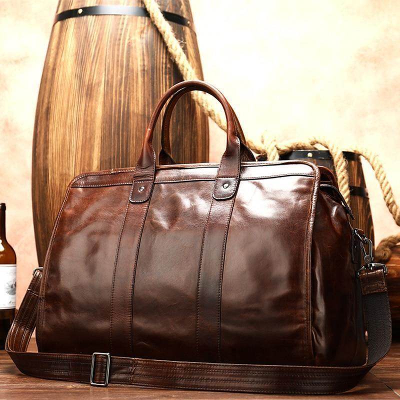 Brown leather shoulder bag for travel with sturdy handles and adjustable strap against a rustic backdrop
