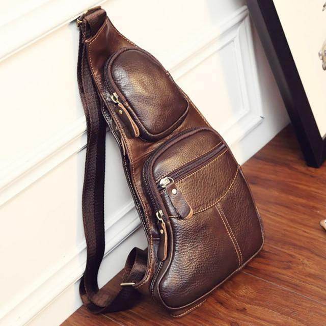 Brown leather sling bag for travel featuring multiple pockets and an adjustable strap