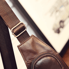 Detail of a leather sling bag for travel showcasing the adjustable strap and pocket design