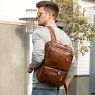 Stylish brown mens 3-in-1 leather combo briefcase backpack worn by man with multiple zip pockets and adjustable straps