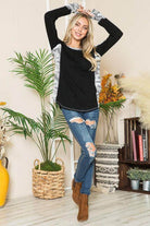 Women's leopard print thumbhole knit shirt with black body and gray sleeves, styled with ripped jeans