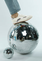 Rag Company lightweight stylish lace up sneakers in white with silver accents on foot over disco ball