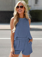 Woman wearing YNIQUE lightweight womens loungewear set in blue with sleeveless top and shorts outdoors