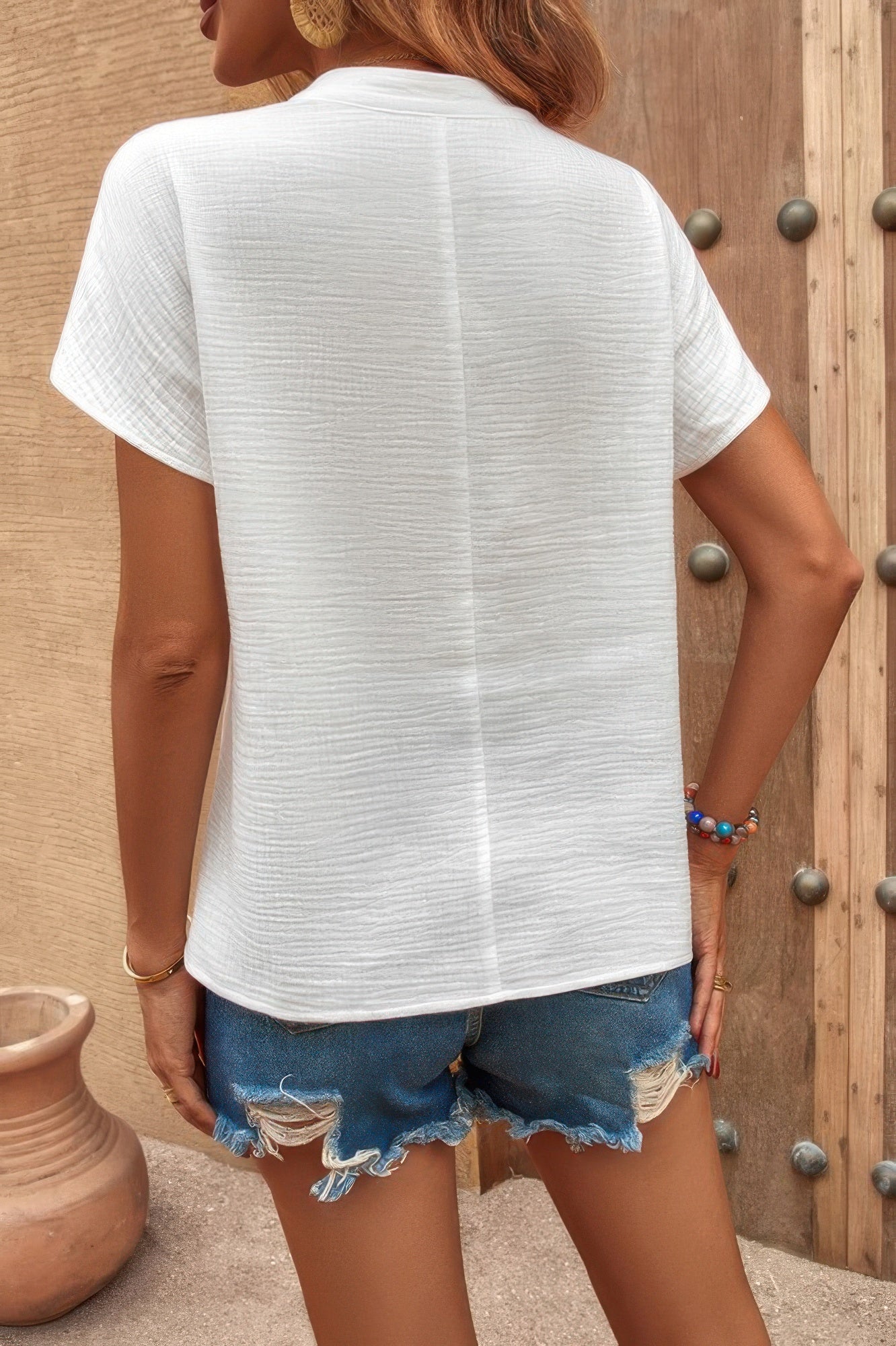 Back view of a loose ruched tank top for women paired with distressed denim shorts