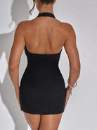 Back view of a woman wearing a black low-cut evening dress for women with halter neck and fitted silhouette