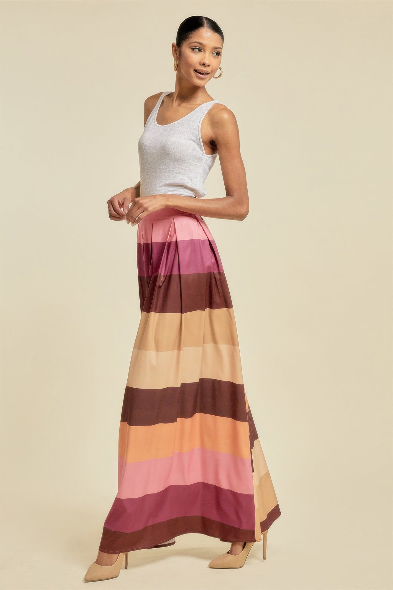 Woman wearing a colorful striped maxi skirt with pockets paired with a white tank top