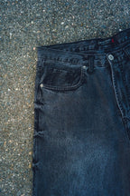 Generation XYZ black mens baggy fit jeans showing front pocket and button detail on textured ground