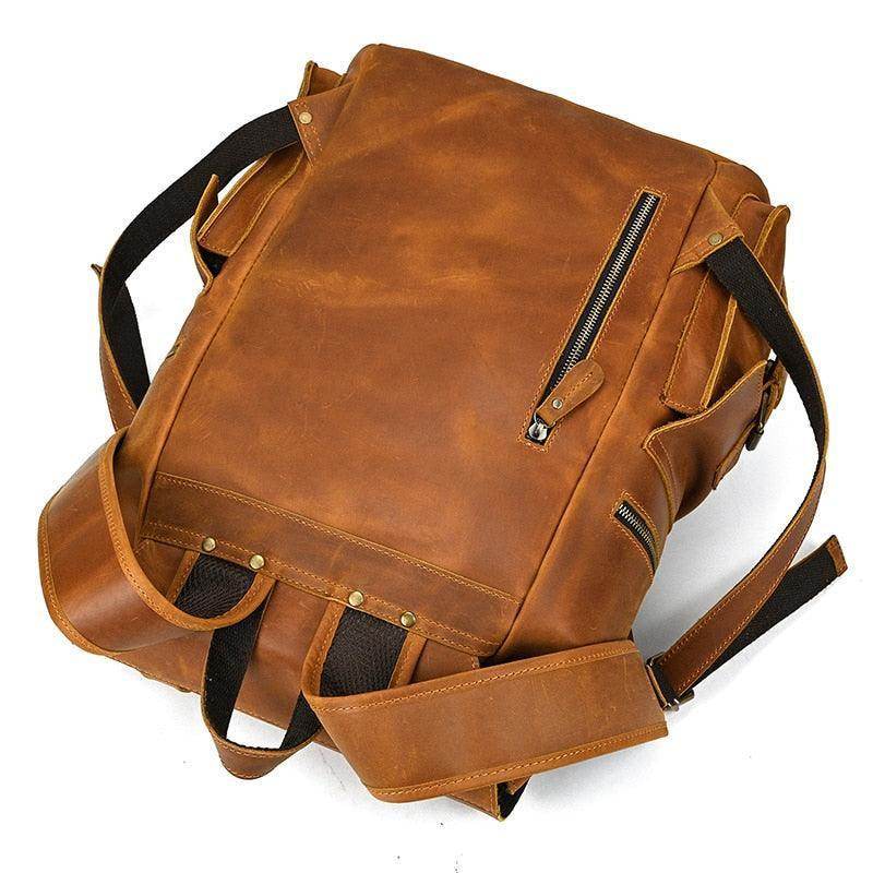 Mens brown leather backpack with rugged design and multiple zippered pockets for travel and daily use
