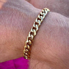 Stylish men's Cuban chain bracelet in gold on a wrist for fashionable accessories