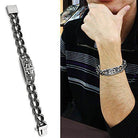 Men's polished stainless steel bracelet with a decorative center link on a model's wrist
