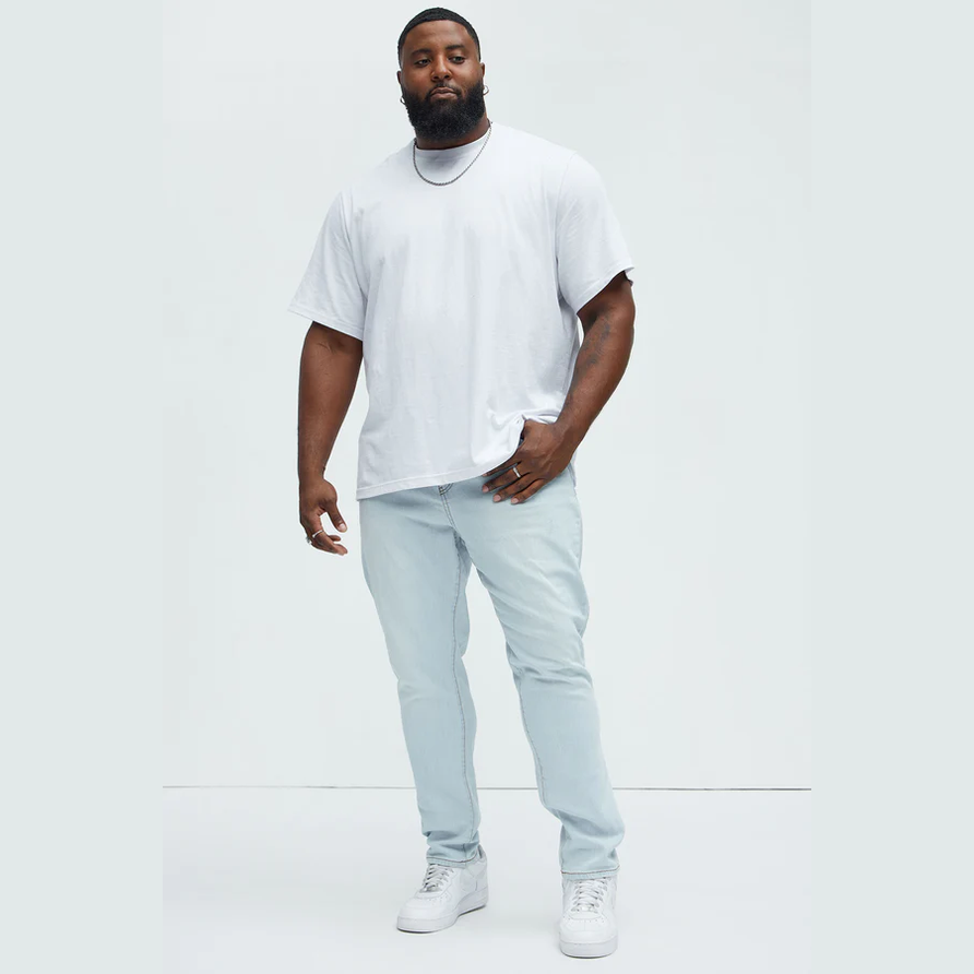 Man wearing mens slim fit jeans light blue paired with a white t-shirt and white sneakers