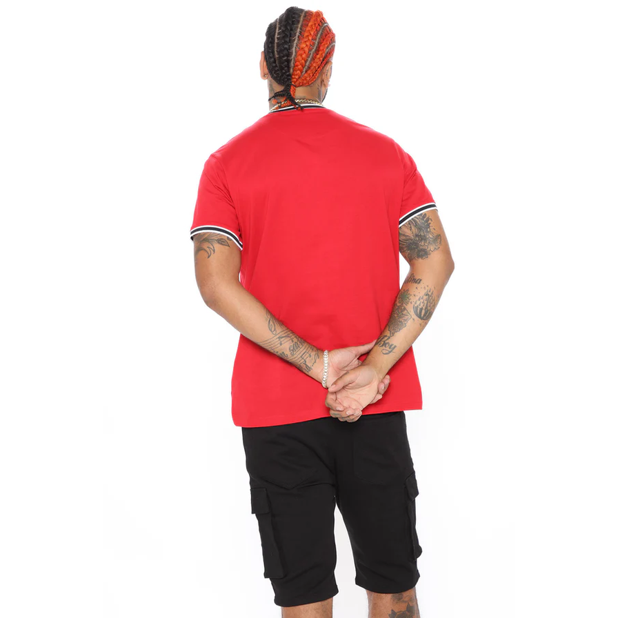 Back view of man wearing red men's vacation graphic tee with black and white trim on sleeves and black shorts