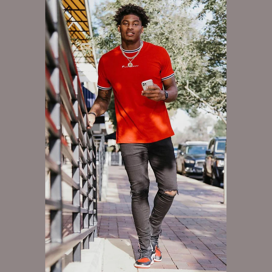 Men's vacation graphic tee in bright red worn by a man walking outdoors on a sunny day