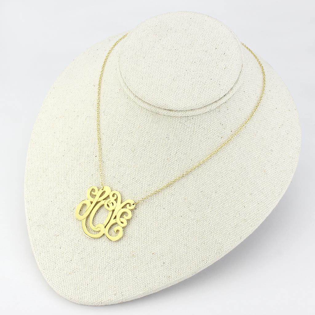 Gold minimalist fashion necklace featuring an elegant monogram design on a display stand