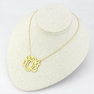 Gold minimalist fashion necklace featuring an elegant monogram design on a display stand
