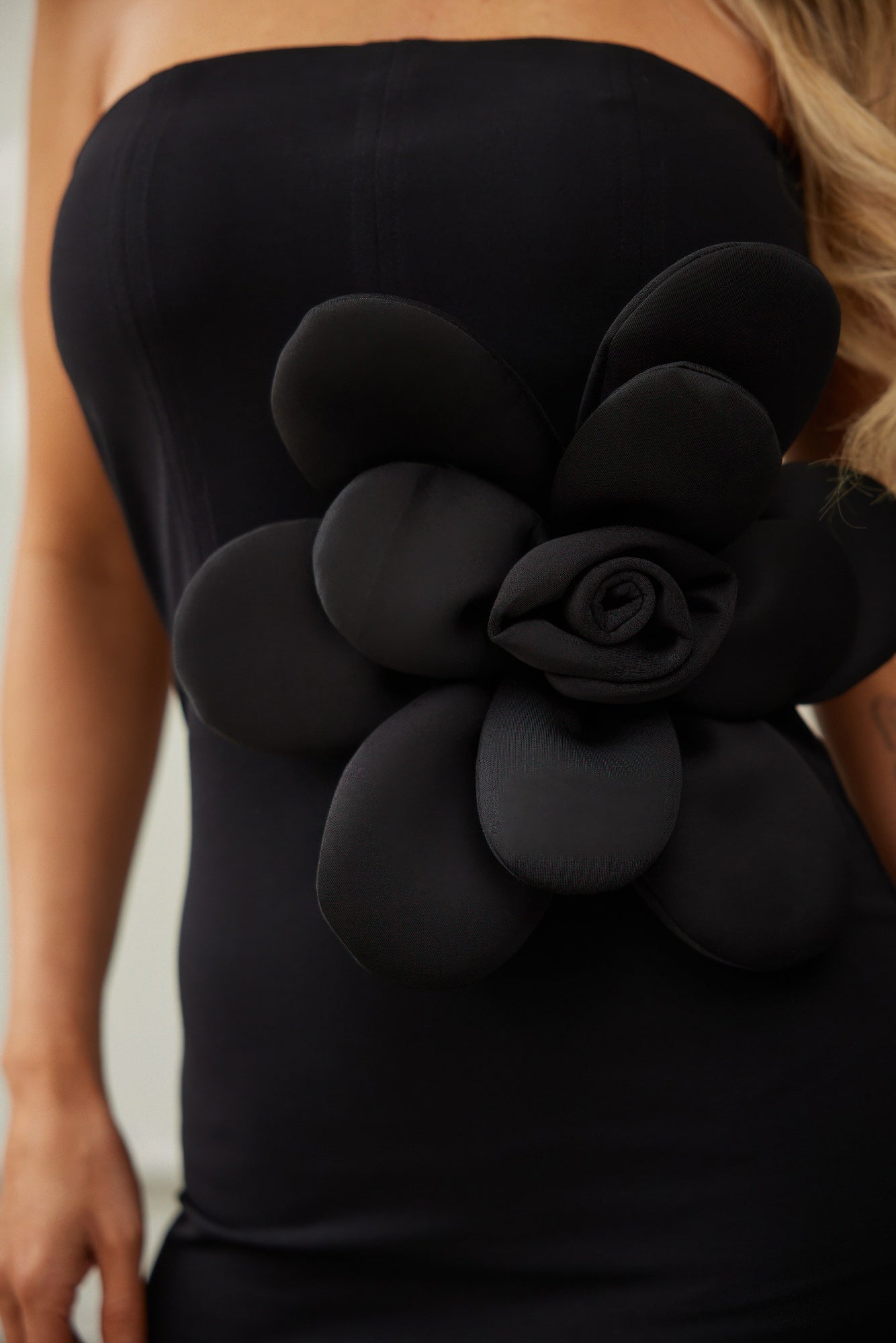 Elegant off shoulder black dress featuring a large floral embellishment for a stylish night out