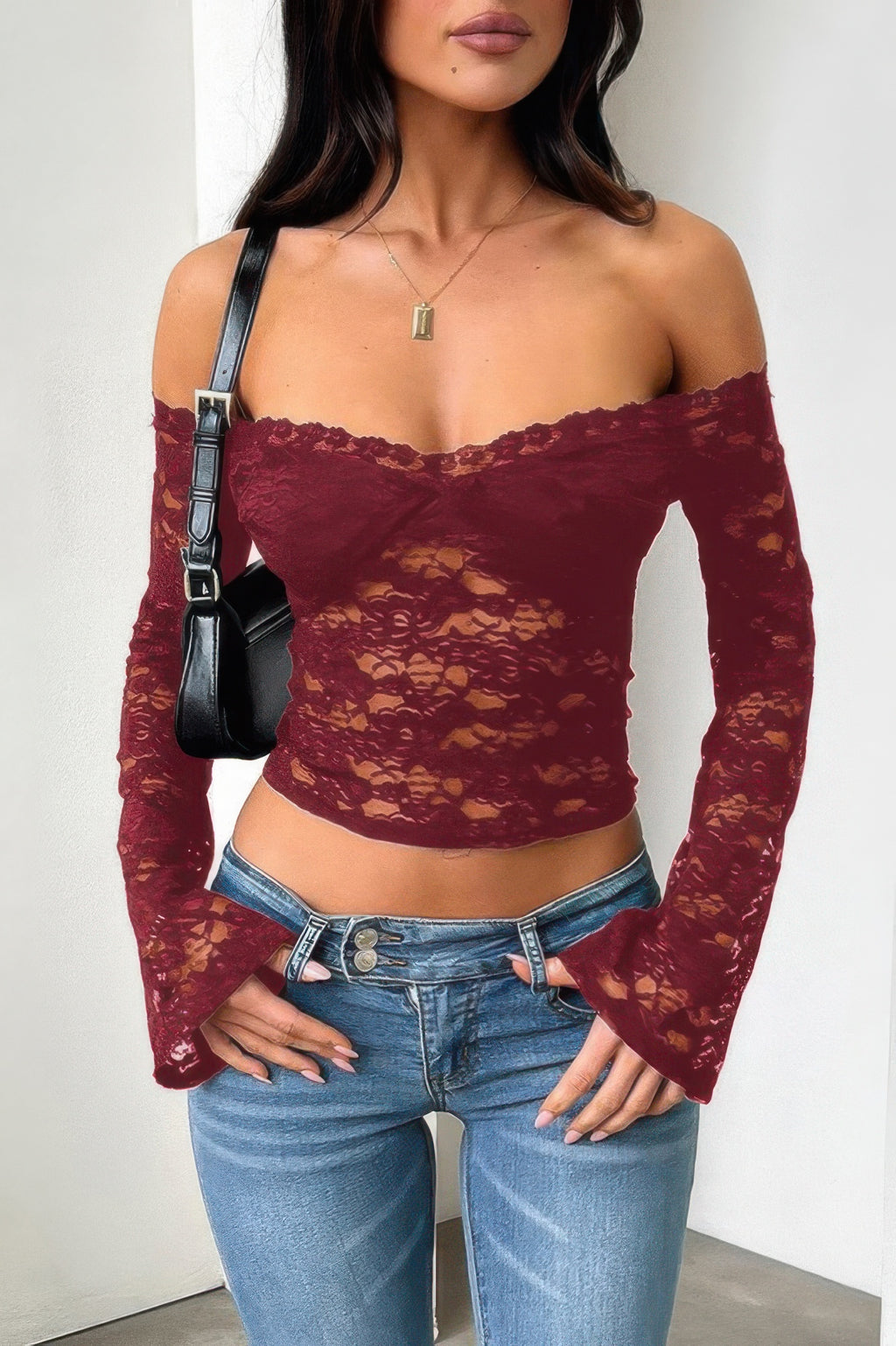 Burgundy off shoulder lace top for women, featuring long sleeves and a fitted design, paired with denim jeans