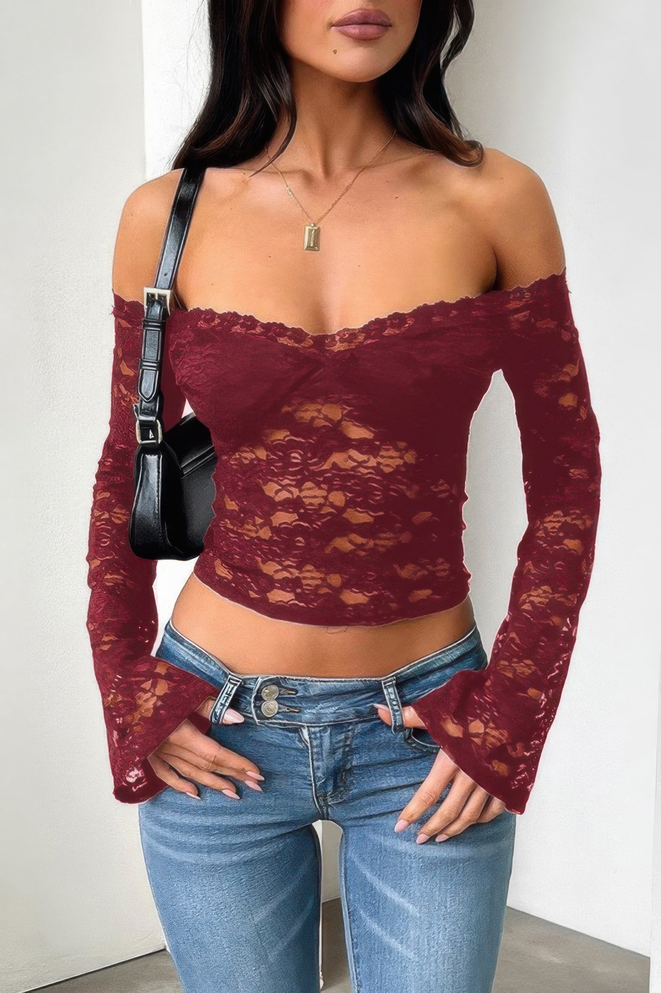 Burgundy off shoulder lace top for women, featuring long sleeves and a fitted design, paired with denim jeans