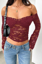 Burgundy women's off shoulder lace top with long sleeves, paired with denim jeans