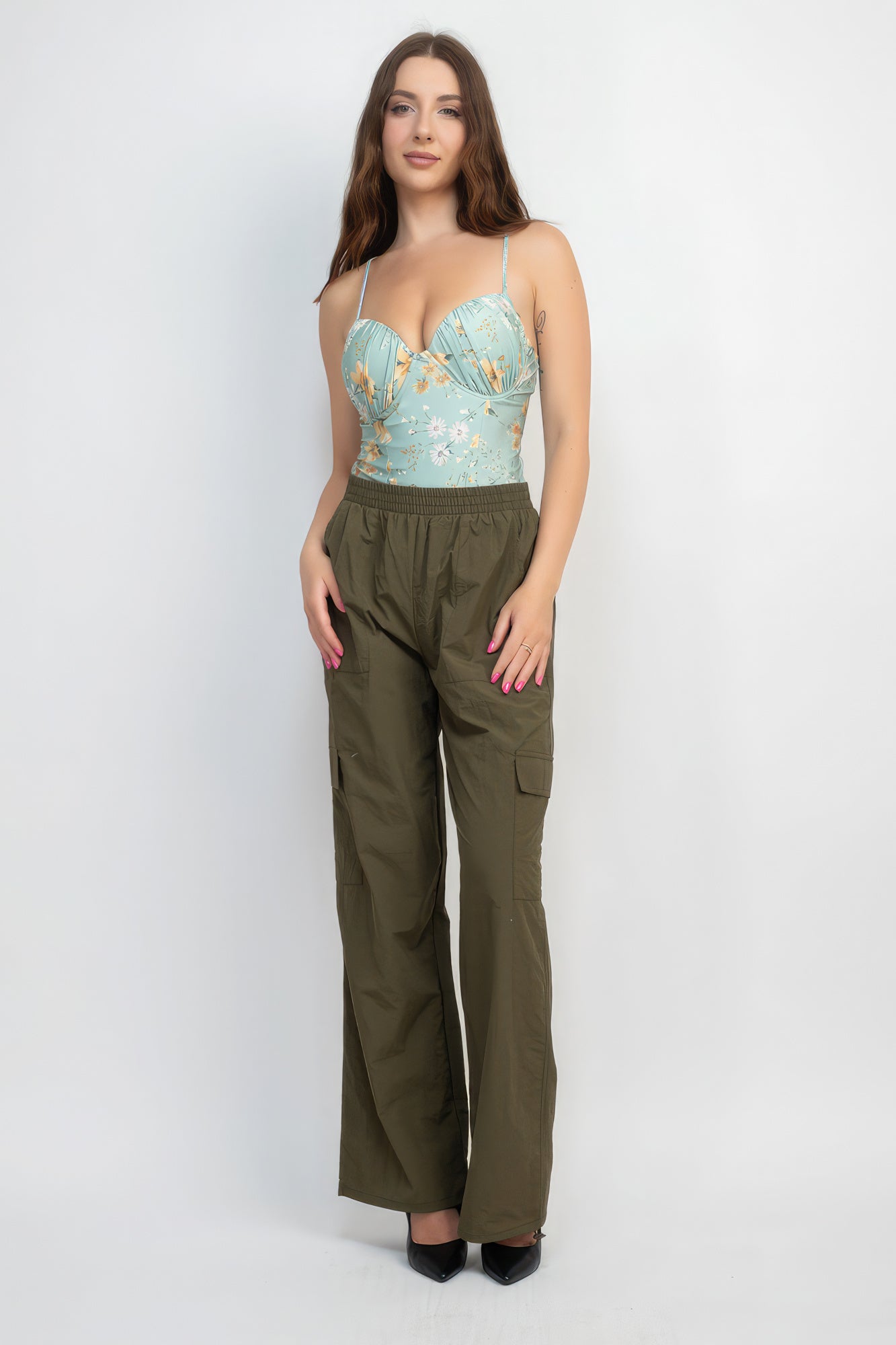 Woman wearing VacationGrabs high-rise cargo parachute pants in olive green with a floral top