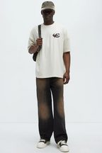 Men wearing oversized graphic tee for men in beige with black and brown pants and beige cap