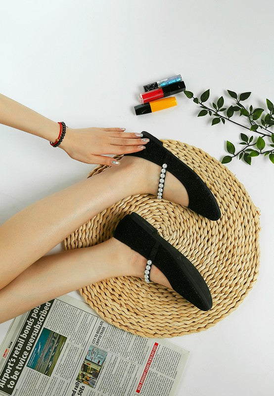Rag Company pearl detail Mary Jane flats in black worn on feet with woven mat and nail polish
