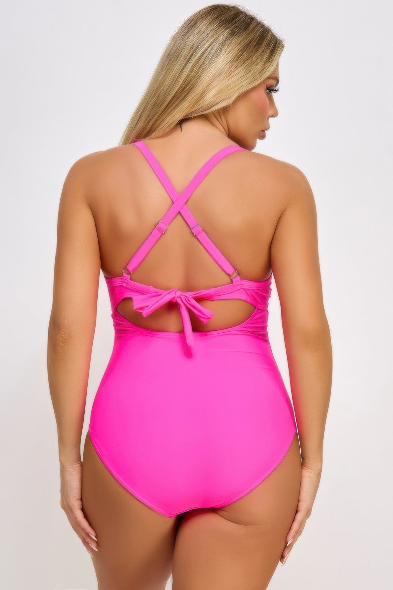 Back view of a pink cutout swimsuit for women with crisscross straps and adjustable tie detail