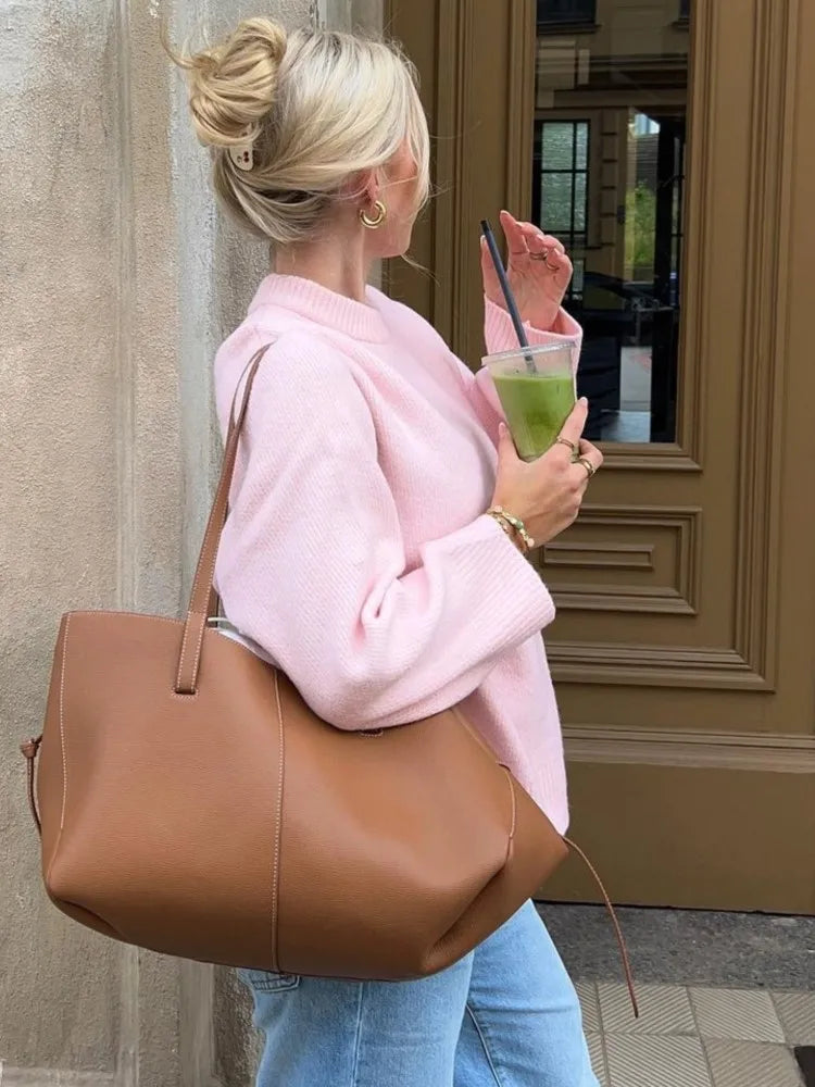Woman wearing a pink oversized sweater for women with a brown handbag and a drink in hand