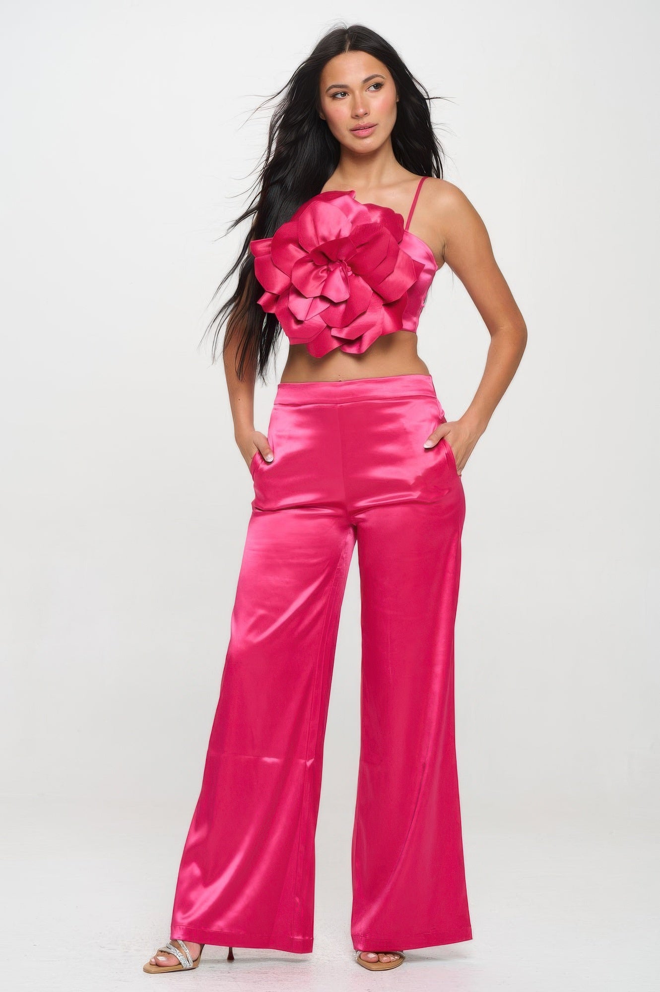 Woman wearing a pink satin crop top and wide leg pants set from VacationGrabs with floral detail on top