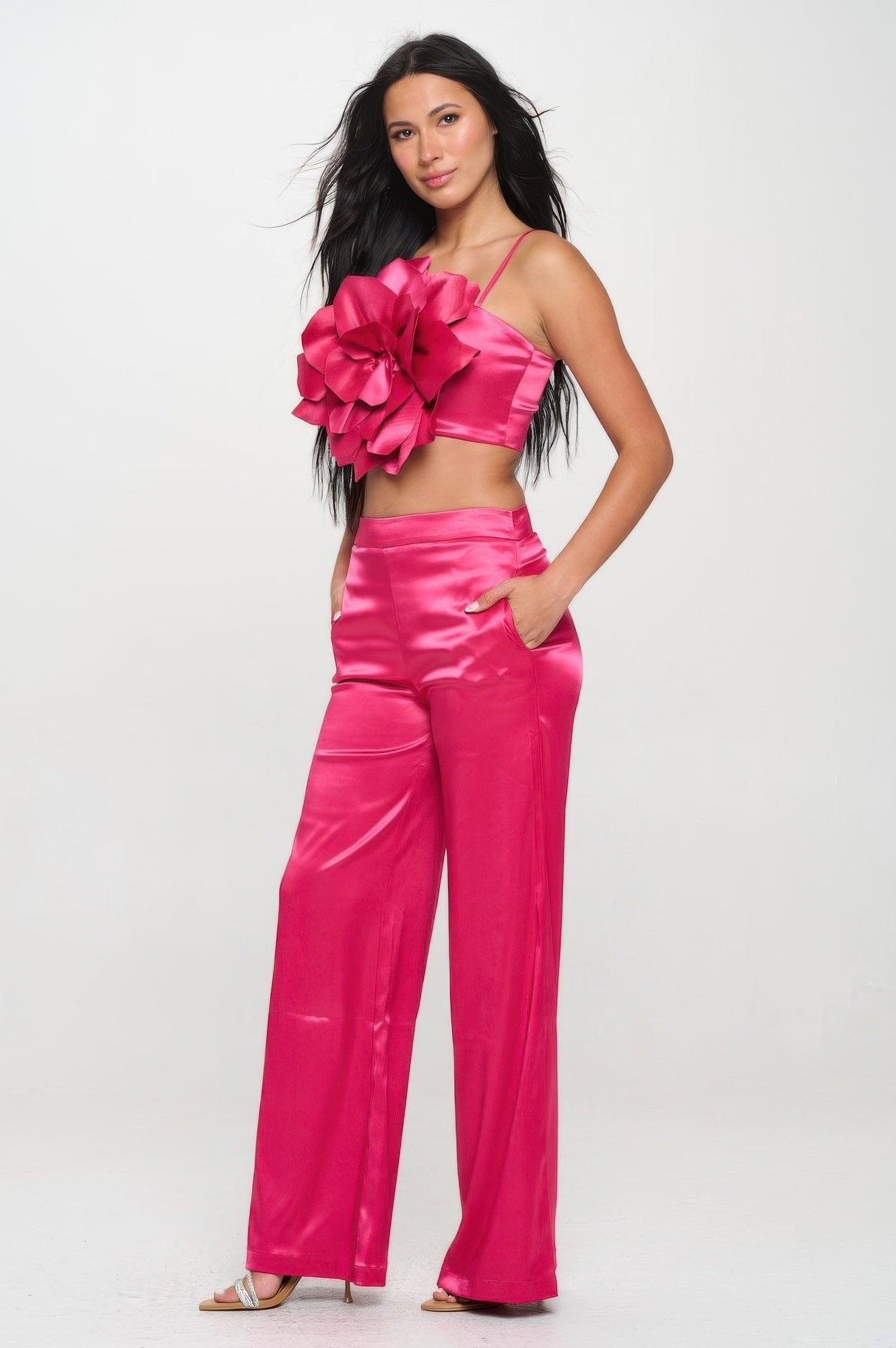 Woman wearing pink satin crop top and wide leg pants set with floral detail and pockets