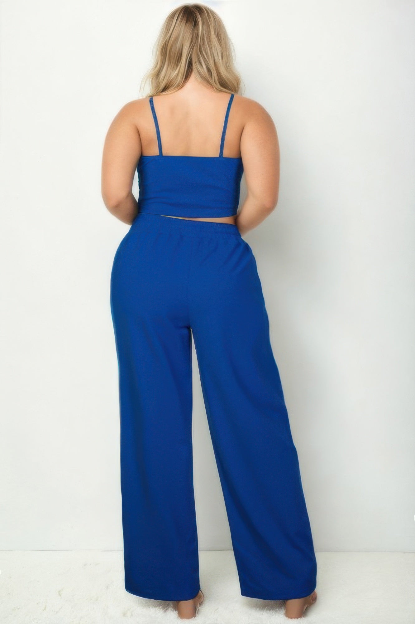 Back view of plus size vacation outfits for women in vibrant blue, featuring a cropped top and wide-leg pants