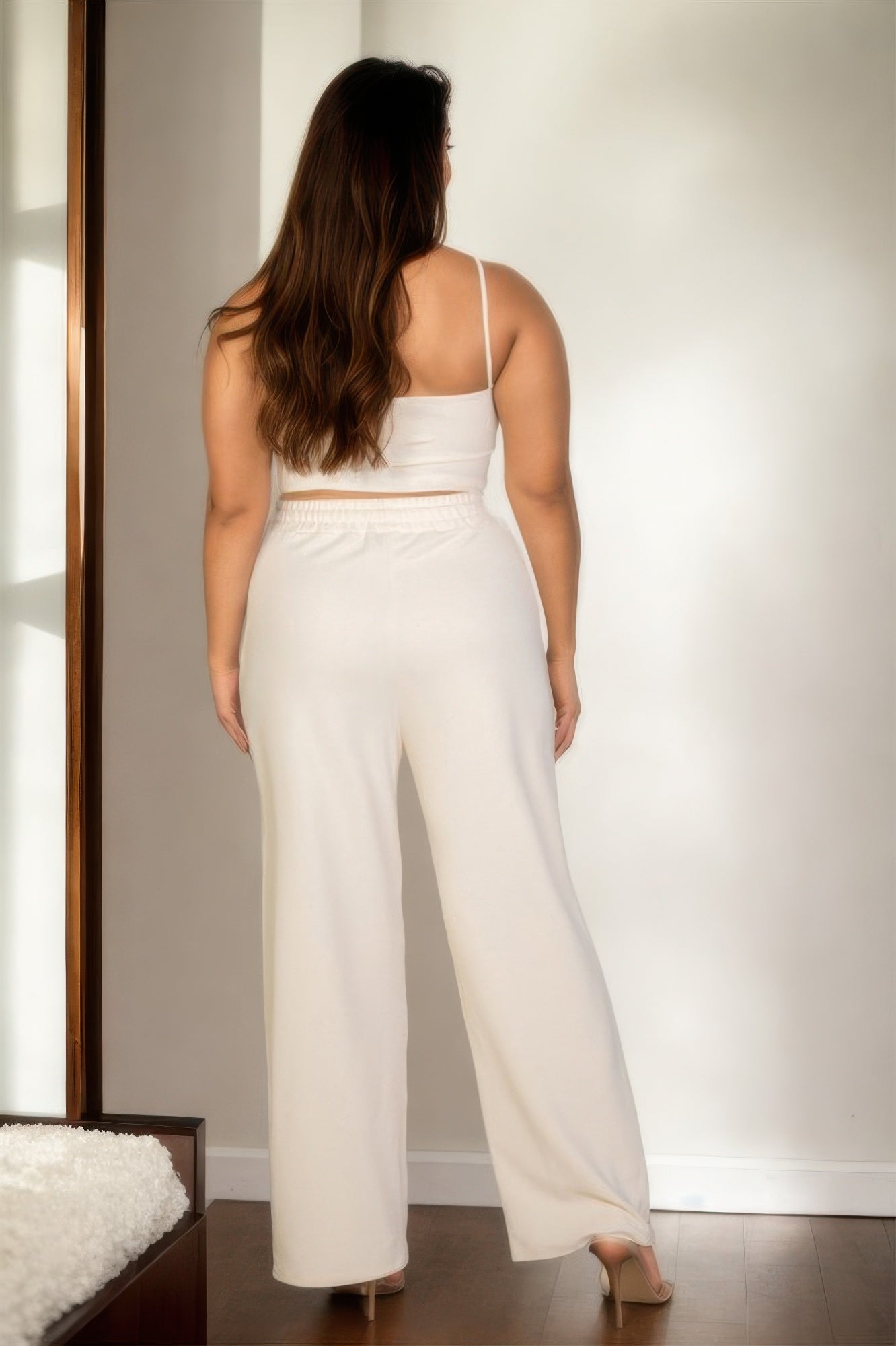 Back view of a plus size vacation outfits for women featuring a cozy cream crop top and wide-leg pants
