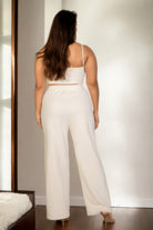 Back view of a plus size vacation outfits for women featuring a cozy cream crop top and wide-leg pants