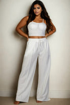 Stylish plus size vacation outfits for women featuring a white crop top and wide-leg pants