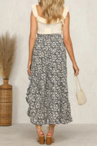 Back view of a woman wearing a polka dot ruffled maxi skirt with a floral top and stylish sandals