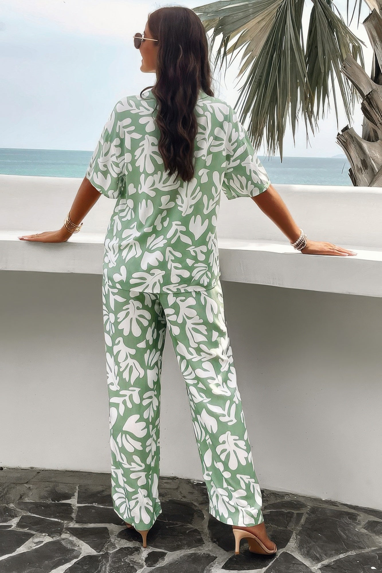Back view of woman wearing green and white printed short sleeve pants set with abstract leaf pattern