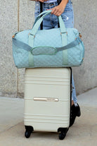 Aili's Corner quilted weekender bag for women in light blue, stylishly placed on top of a suitcase