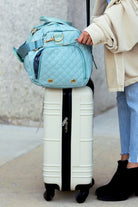 Aili's Corner quilted weekender bag for women in light blue, stylishly placed on top of a suitcase