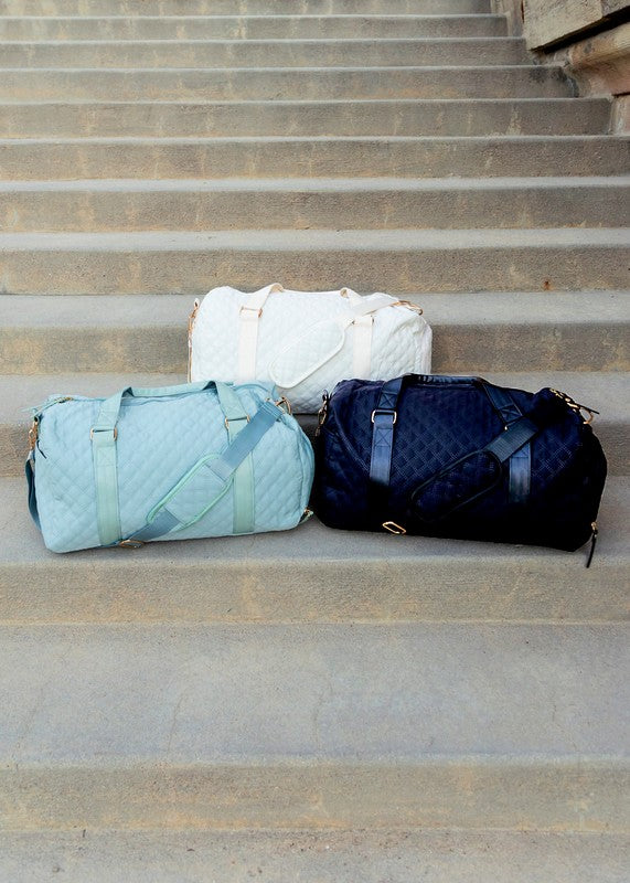 Quilted weekender bag for women in light blue, white, and navy, perfect for travel and style.