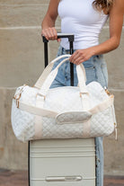 Aili's Corner quilted weekender bag for women in white, stylishly held on a suitcase for travel