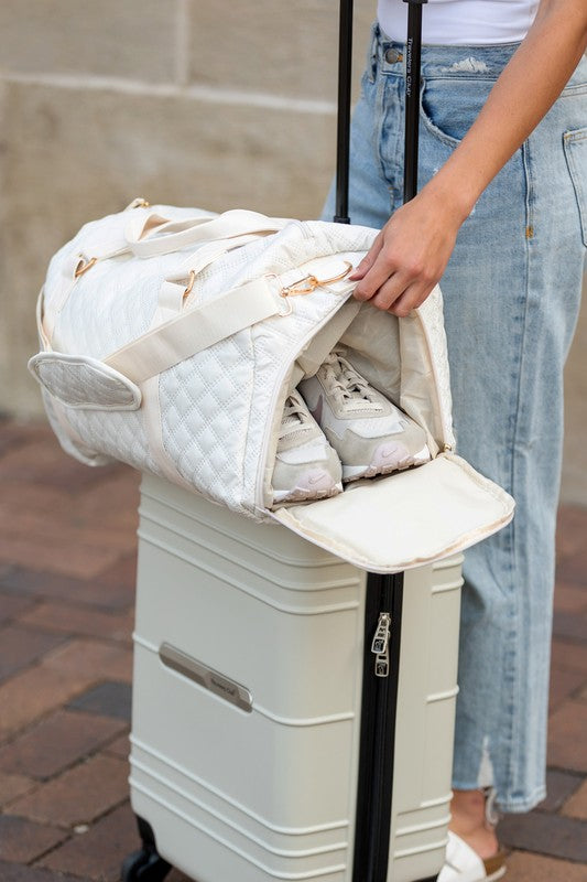 Aili's Corner quilted weekender bag for women being packed over a suitcase with shoes inside