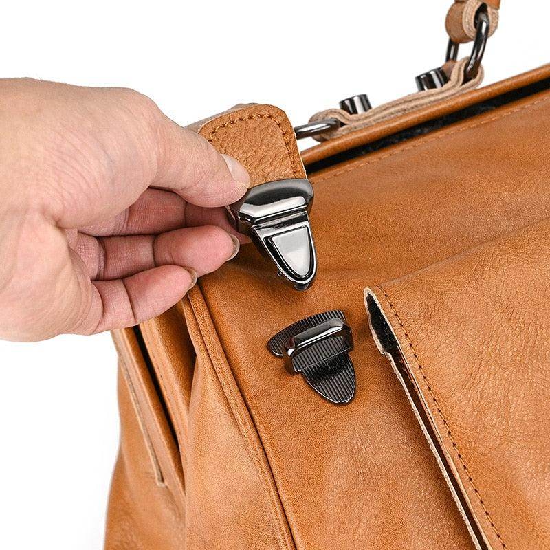Close-up of a hand holding a buckle on a real leather travel bags featuring durable hardware