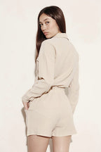 Woman wearing a beige relaxed fit button down shorts set by Miss Sparkling with long sleeves and shorts