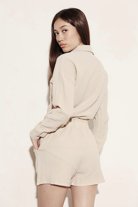 Woman wearing a beige relaxed fit button down shorts set by Miss Sparkling with long sleeves and shorts